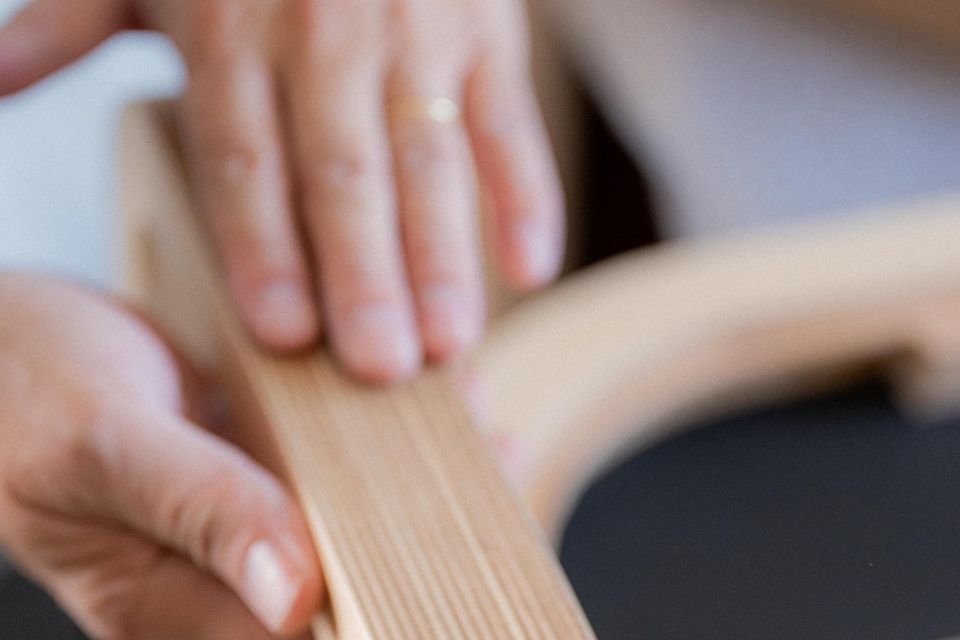 Manos trabajando láminas de madera sobre el banco del taller.